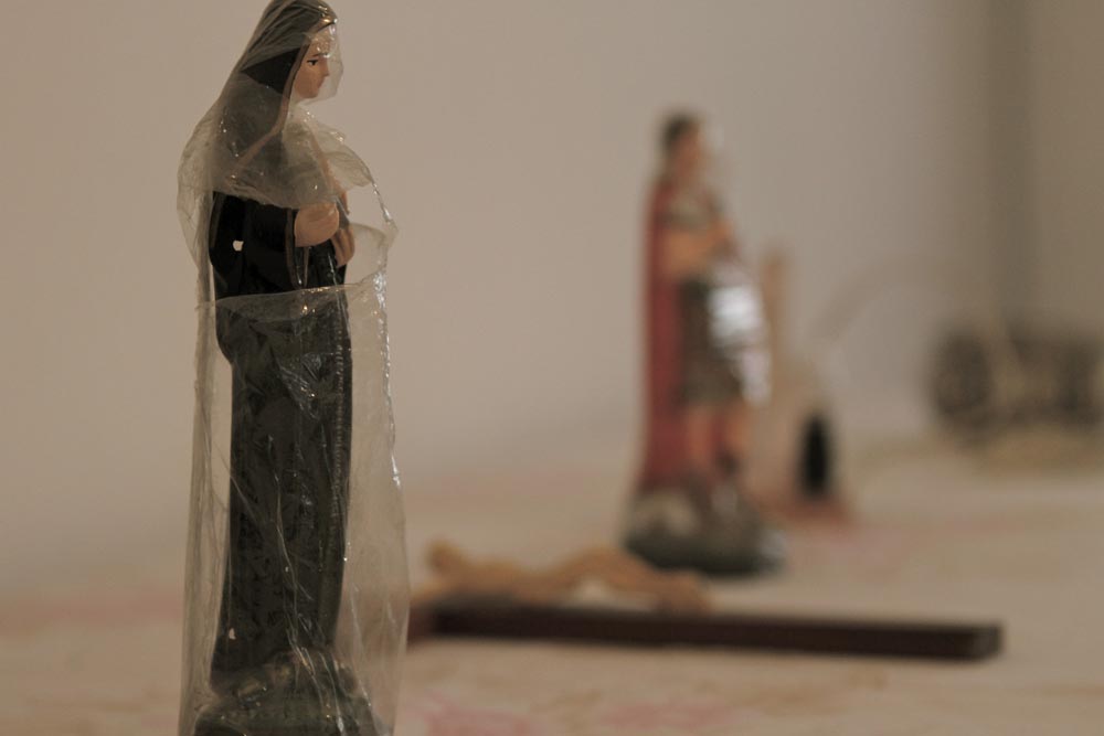 Imagem de santa de porcelana ainda envolta no plástico original, sobre uma superfície clara.